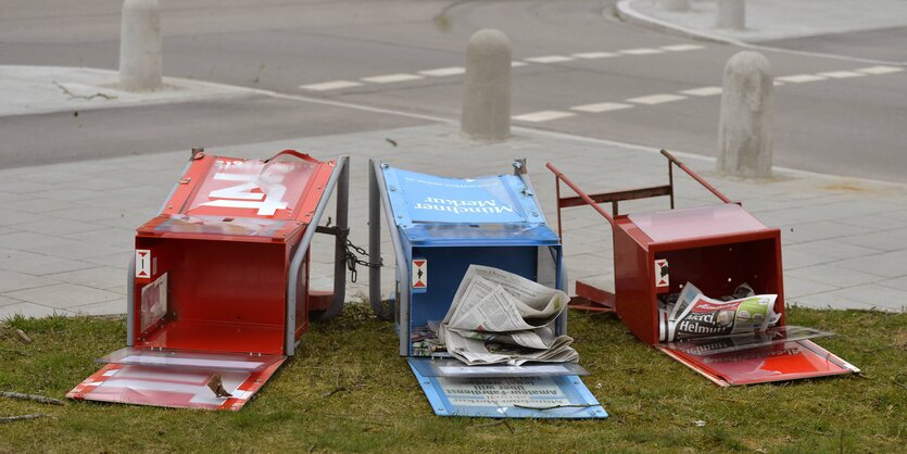 Am Straßenrand liegen drei Kästen, aus denen man sich Zeitungen nehmen kann.