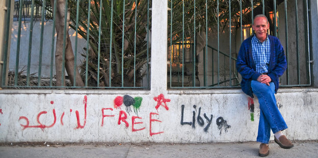 Ein Mann sitzt auf einer Mauer, auf der „Free Libya“ geschrieben steht