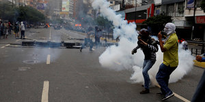 Zwei Demonstranten stehen im Tränengasnebel