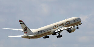 Ein Etihad-Flugzeug steigt vor blaßblauem Himmel auf