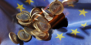 Geldmünzen fallen auf eine Flagge der Europäischen Union