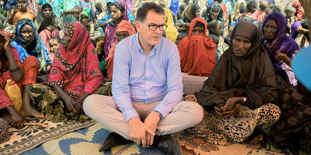 Gerd Müller sitzt im Schneidersitz zwischen Somalieriennen