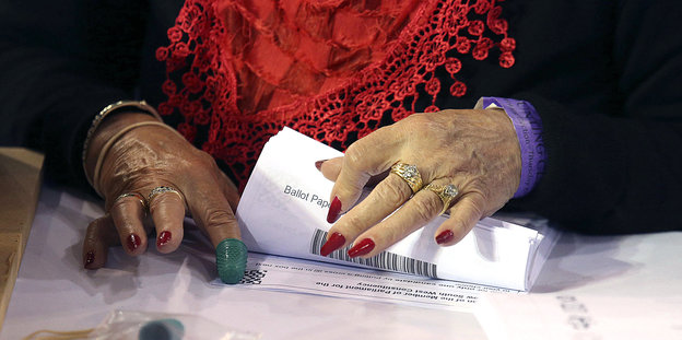 Frauenhände mit lackierten Fingenägeln und Fingerhut zählt Wahlzettel
