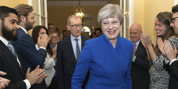 Theresa May geht lächelnd durch eine Gruppe Applaudierender