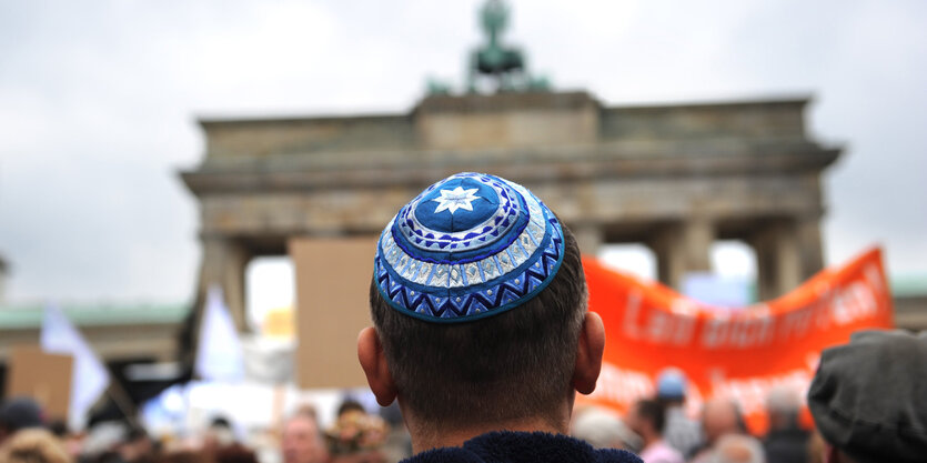 Ein Mann mit einer Kippa von hinten, im Hintergrund das Brandenburger Tor