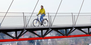 Ein Mann fährt Fahrrad auf einer Brücke