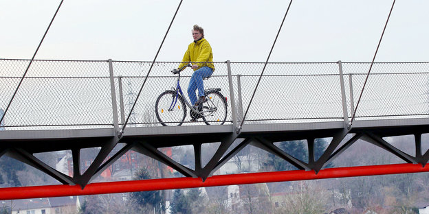 Ein Mann fährt Fahrrad auf einer Brücke