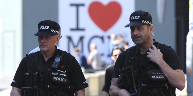 Zwei Polizisten in Sicherheitswesten, im Hintergrund ein rotes Herz