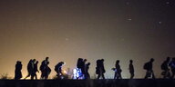 Eine Gruppe von Menschen nachts auf der Flucht