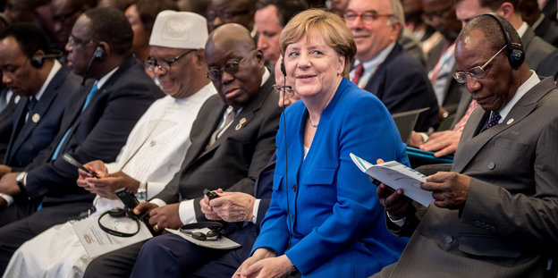 Angela Merkel sitzt zwischen afrikanischen Staatschefs und lächelt