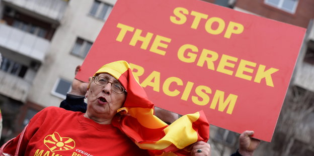 Ein Mazedonier demonstriert mit einem Plakat in der Hand. Darauf steht "Stoppt den griechischen Rassismus".