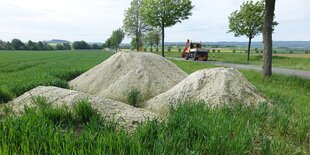 drei Sandhaufen neben einer Allee auf dem flachen Land