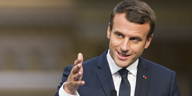 Emmanuel Macron im Porträt gestikuliert vor einem Mikrofon