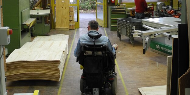 Ein Mann fährt im Rollstuhl auf eine Tür zu