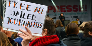 Konzertbesucherin hält Schild: "Free all jailed journalists"