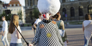 Ein Clown vor dem Theater in Dresden beim Selfie