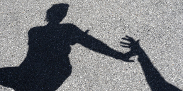 Man sieht den Schatten einer Frau, die sich gegen die Hand eines Mannes wehrt.