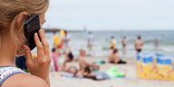 Eine Frau telefoniert mit einem Handy am Strand