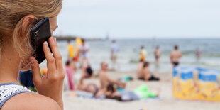 Eine Frau telefoniert mit einem Handy am Strand