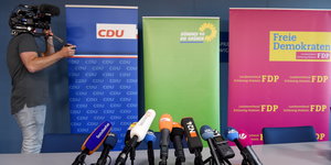 Ein Kameramann filmt die Aufsteller von CDU, Grünen und FDP vor der Pressekonferenz