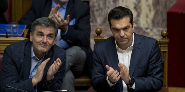 Tsipras und Tsakalotos applaudieren mit finsteren Minen