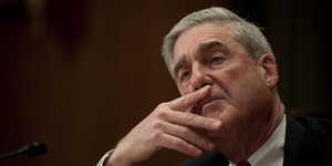 Robert Mueller sitzt vor schwarzem Hintergrund, guckt sinnierend in die Luft und hat den Kopf auf seine rechte Hand gestützt