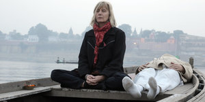 Jutta Winkelmann meditiert auf einem Boot sitzend in Indien, neben ihr liegt ihr Partner Rainer Langhans.