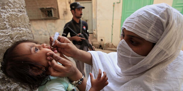 Ein Frau verabreicht einem Kind eine Impfstoffdosis