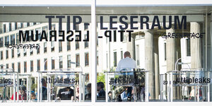 Ein Mann sitzt in einem gläsernen Raum mit der Aufschrift "TTIP-Leseraum" - "#ttipleaks"