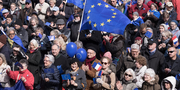 Viele dicht stehende Menschen, über ihnen die blaue Europafahne.