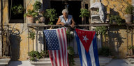 Ein Mann steht auf einem Balkon, an dem eine kubanische und eine US-Fahne hängen.