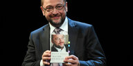 Martin Schulz hält ein Buch mit Martin-Schulz-Foto auf dem Cover in den Händen