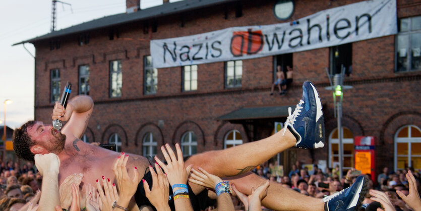 Ein Mann wird bei einem Konzert vor dem Kulturbahnhof auf Händen getragen.