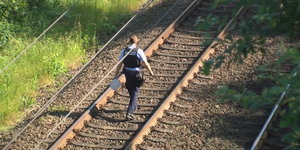 ein Polizist läuft einen Bahndamm entlang