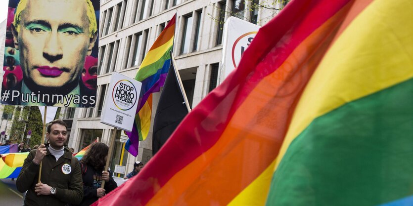 Eine Demo mit Regenbogenflaggen und einem Plakat mit einem geschminkten Putin