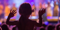 Ein Mädchen reckt vor einer Bühne die Hände in die Höhe