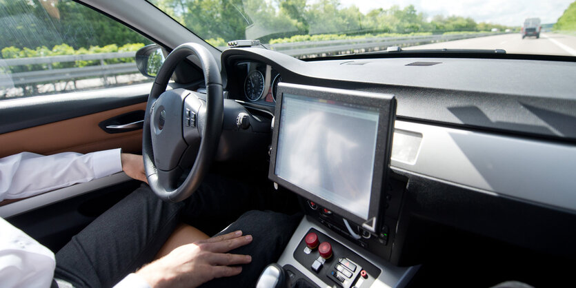 Ein Mensch in einem Auto, die Hände neben dem Lenkrad abgelegt