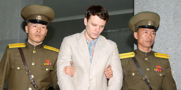 Ein Mann in hellem Jacket, abgeführt von zwei Uniformierten