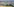Blick auf eine hügelige Landschaft in Italien. Im Vordergrundein Wohnhaus zwischen Bäumen