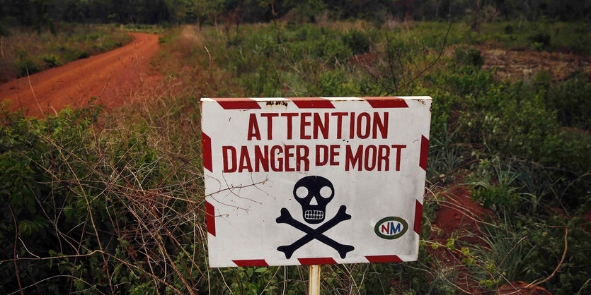 Ein Schild mit einem Totenkopf und der französischen Aufschrift „Achtung, Todesgefahr“ steht am Straßenrand