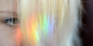 Auf den Haaren einer Person schimmert regenbogenfarbenes Licht