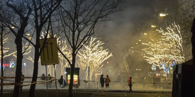 Menschen stehen auf einer Straße mit beleuchteten Bäumen