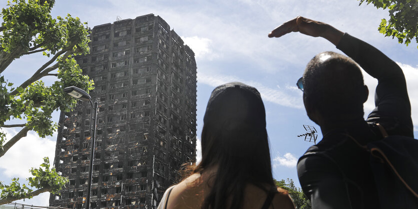 Ein Mann und Frau schauen auf die Grenfell Towers