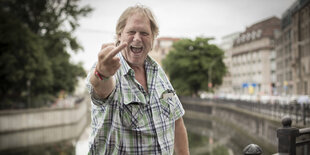 Gunter Gabriel im karierten Hemd zeigt lachend seinen Mittelfinger.