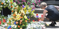 Maike Kohl-Richter bückt sich zu den Blumen, die vor ihrem Haus in Oggersheim abgelegt wurden