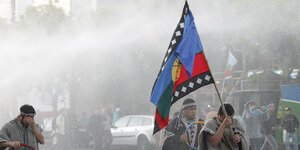 Drei chilenische Mapuche demonstrieren, zwei von ihnen tragen eine blau-rote Flagge