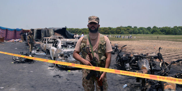 Ein pakistanischer Soldat steht an der Unfallstelle hinter gelbem Absperrband
