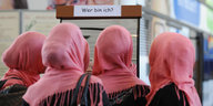 Vier junge Frauen von Hinten mit Kopftüchern in demselben Rosaton