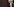 Maike Kohl-Richter steht im schwarzen Etuikleid und mit Sonnenbrille und gesenktem Kopf vor dunklem Hintergrund