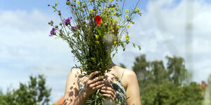 Eine Frau hält sich Blumen vors Gesicht